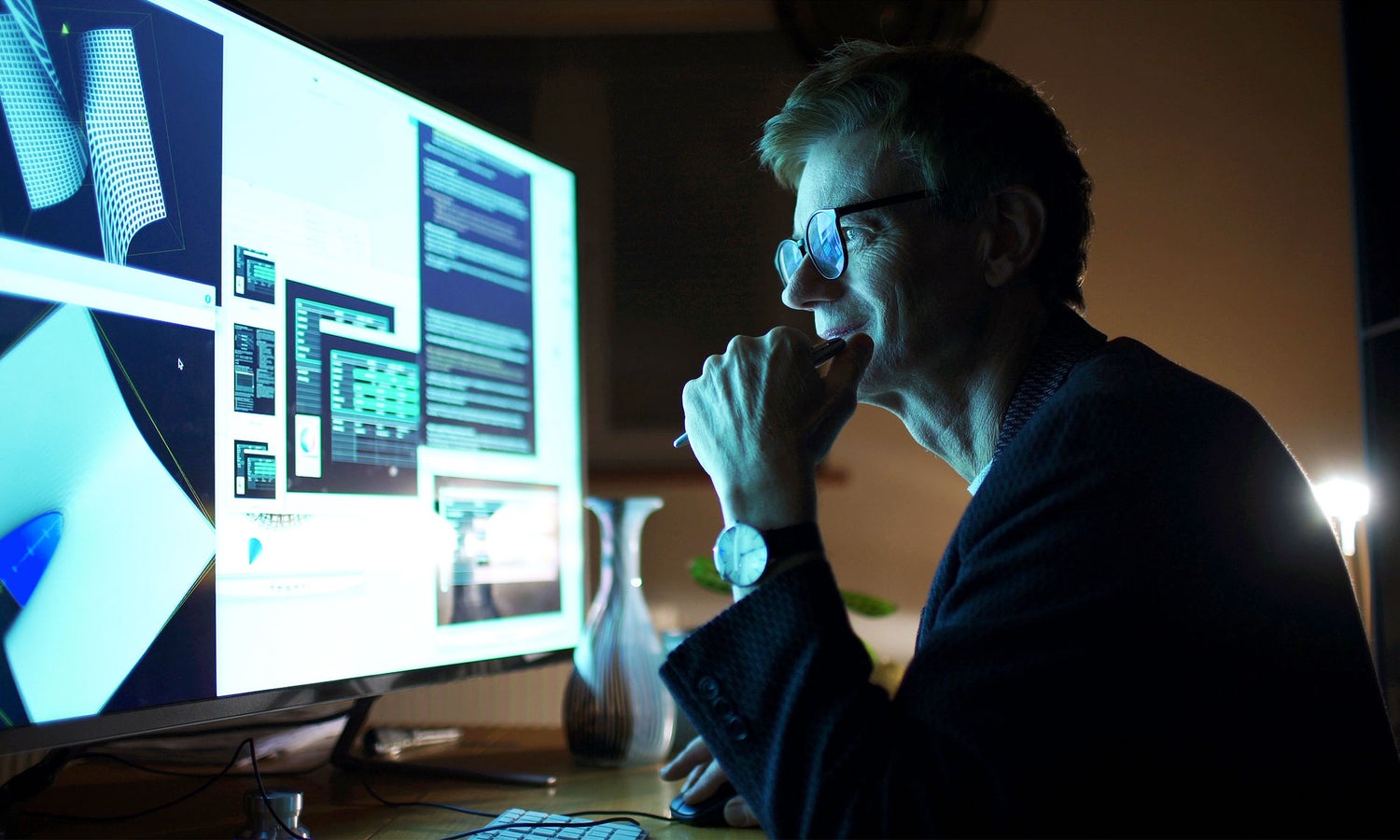 Person at desk contemplating various layouts, structures, and designs on a large computer screen